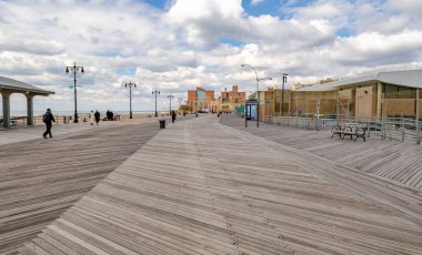 Güneşli kış gününde New York 'ta insanların yürüdüğü Coney Adası' ndaki sahil gezisi.