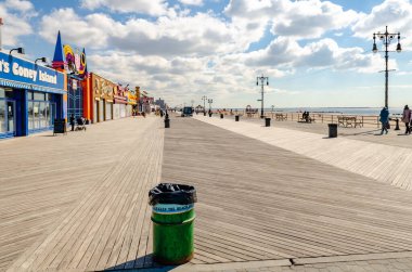 Coney Adası 'ndaki sahil güvertesinde bir sürü dükkan ve New York sahilinin yanında yürüyen insanlar var.