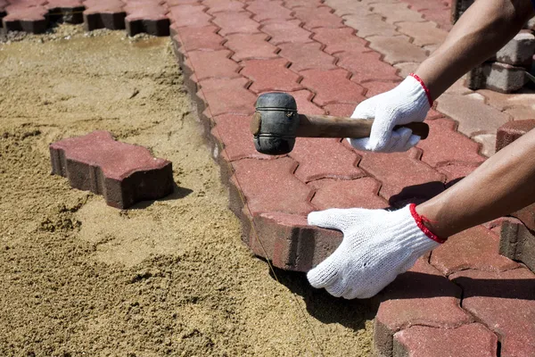 Un trabajador colocando adoquines de hormigón rojo . —  Fotos de Stock