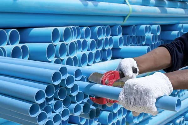 Arbetstagaren skär pvc pipe i byggarbetsplatsen — Stockfoto