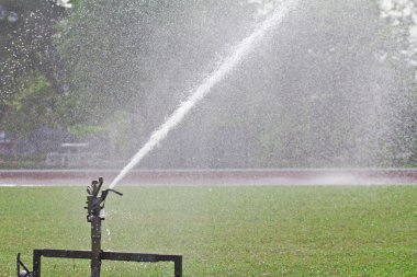 Sprinkler spraying water over lawn clipart