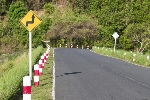 Дорожній знак попереджає про різкий поворот на вузькій дорозі — стокове фото