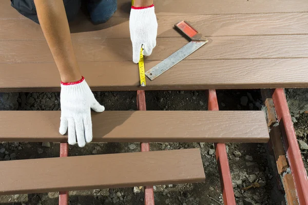 Lavoratore installazione pavimento in legno per patio — Foto Stock