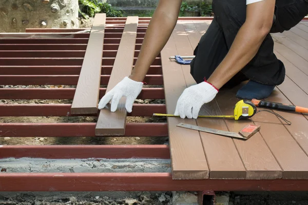 Lavoratore installazione pavimento in legno per patio — Foto Stock