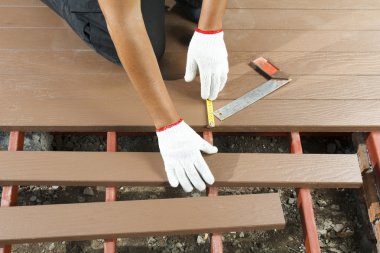 Worker installing wood floor for patio clipart