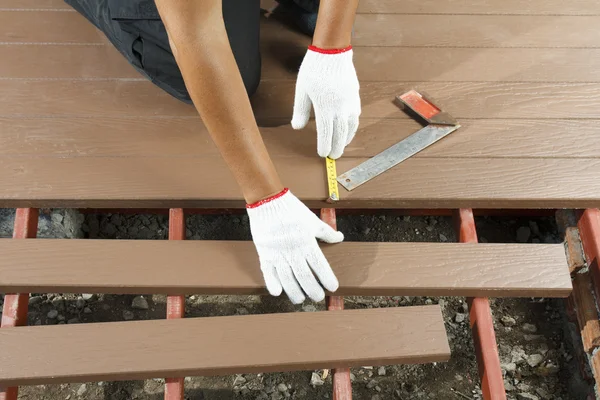 Lavoratore installazione pavimento in legno per patio — Foto Stock