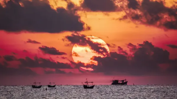 Fisherman on the boat over dramatic sunrise — Stock Photo, Image