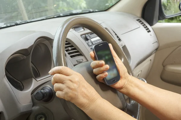 Senior mulher dirigindo carro e chamando com telefone celular — Fotografia de Stock