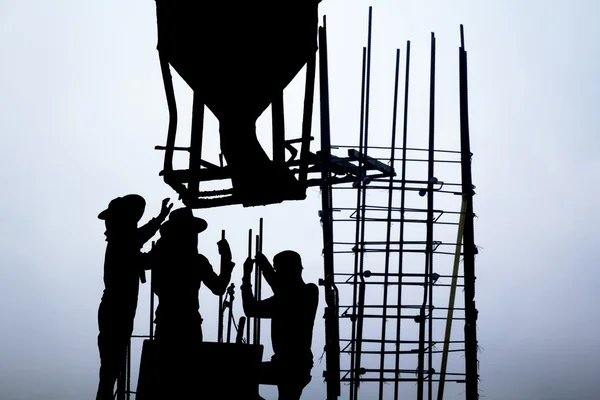 Бетонное ведро над рабочими на строительной площадке — стоковое фото