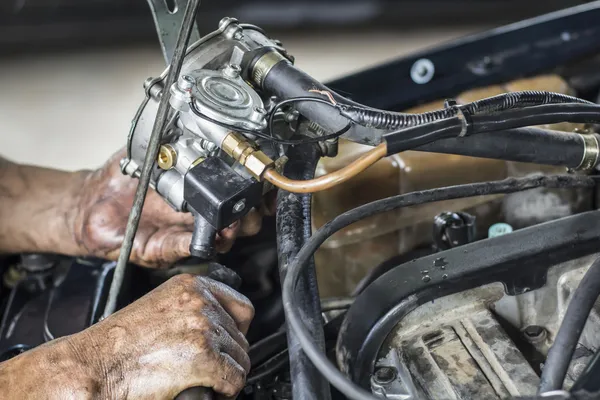 Mechanic устанавливает новый газовый испаритель в старом автомобиле — стоковое фото