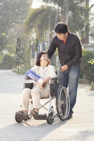 Asian man taking his elderly mother for a walk in the morning — Stock Photo, Image