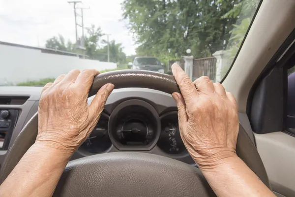 Äldre kvinna kör bil långsamt i stan — Stockfoto