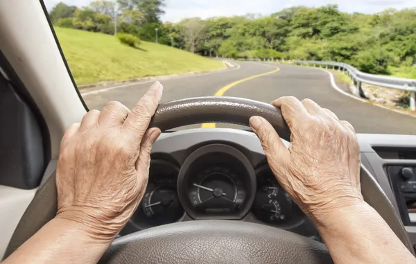 Старшая женщина медленно водит машину по шоссе — стоковое фото