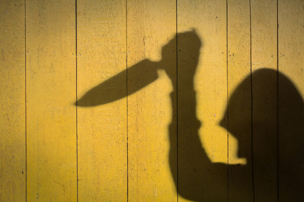 Male Hand Shadow with Kitchen Knife, on wood wall