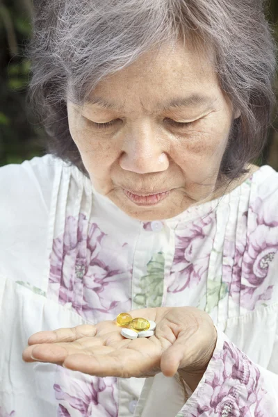 Mujer mayor asiática mirando píldoras —  Fotos de Stock