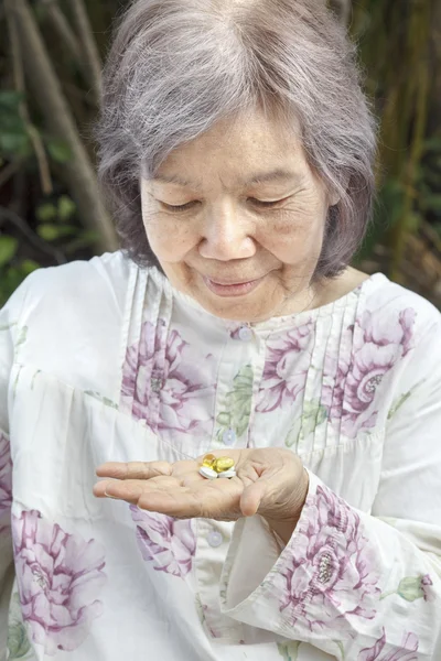 Asiatische Seniorin schaut sich Pillen an — Stockfoto
