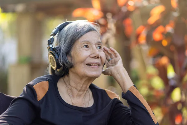 Asiatisk Senior Kvinna Lyssnar Musik Med Hörlurar Trädgården — Stockfoto