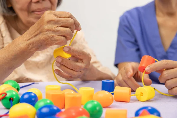 照顾者和老年妇女玩预防痴呆症的串珠游戏 — 图库照片