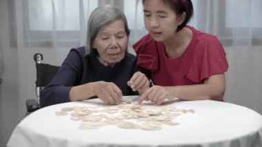 Yaşlı bir kadın kızıyla ruh sağlığı ve hafızasını geliştirmek için alfabe oyunları oynuyor.