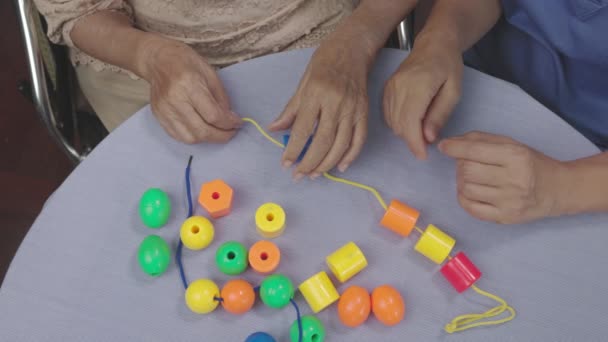 Cuidador Mulher Sênior Jogando Stringing Beads Jogo Para Prevenção Demência — Vídeo de Stock