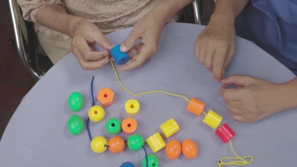 Cuidador Mulher Sênior Jogando Stringing Beads Jogo Para Prevenção Demência — Vídeo de Stock