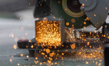 Takım yıldız bölgesinde çelik kare boru kesen işçiler.