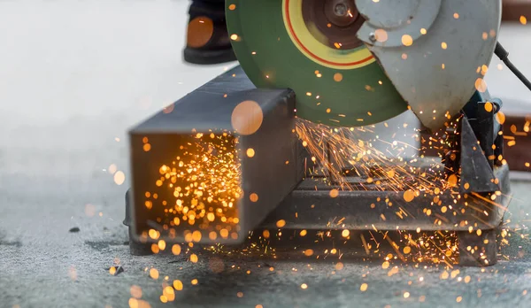 Takım yıldız bölgesinde çelik kare boru kesen işçiler.