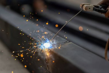 worker welding steel pipe in construction site clipart