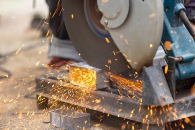 İnşaat alanında çelik dikdörtgen boru kesen işçiler.
