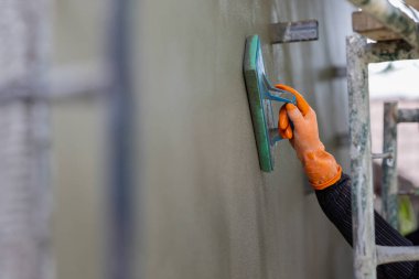 Profesyonel müteahhit duvarı süngerle kaplayarak pürüzsüz bir şekil veriyor..