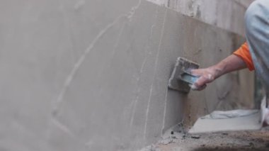 İnşaat işçisi duvar yüzeyini sıva yapıyor..
