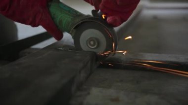 Worker cutting steel rectangular pipe in construction site.
