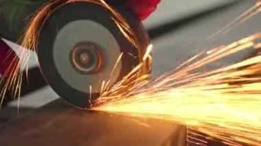 Worker cutting steel rectangular pipe in construction site.