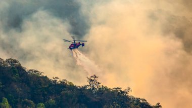 Yangın söndürme helikopteri yangına su bırakıyor.