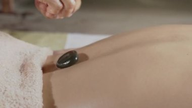 Stone treatment. Asian female gets hot stone massage therapy in spa salon. Healthy lifestyle and body care concept..