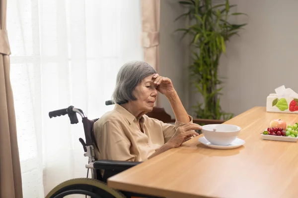 Lonely senior asian woman bored with food.