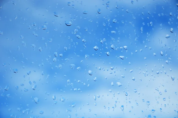 Cielo azul visible a través de la ventana con gotas de lluvia — Foto de Stock