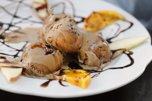 Coffee ice-cream with chocolate sirup and slices of orange on white plate — Stock Photo, Image