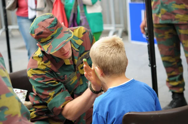 Uidentifisert soldat viser hvordan man sminker seg på Belgias nasjonaldag. – stockfoto