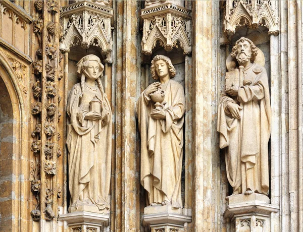 Tres personajes medievales a la entrada en la iglesia católica Petit Sablon en Bruselas, Bélgica — Foto de Stock