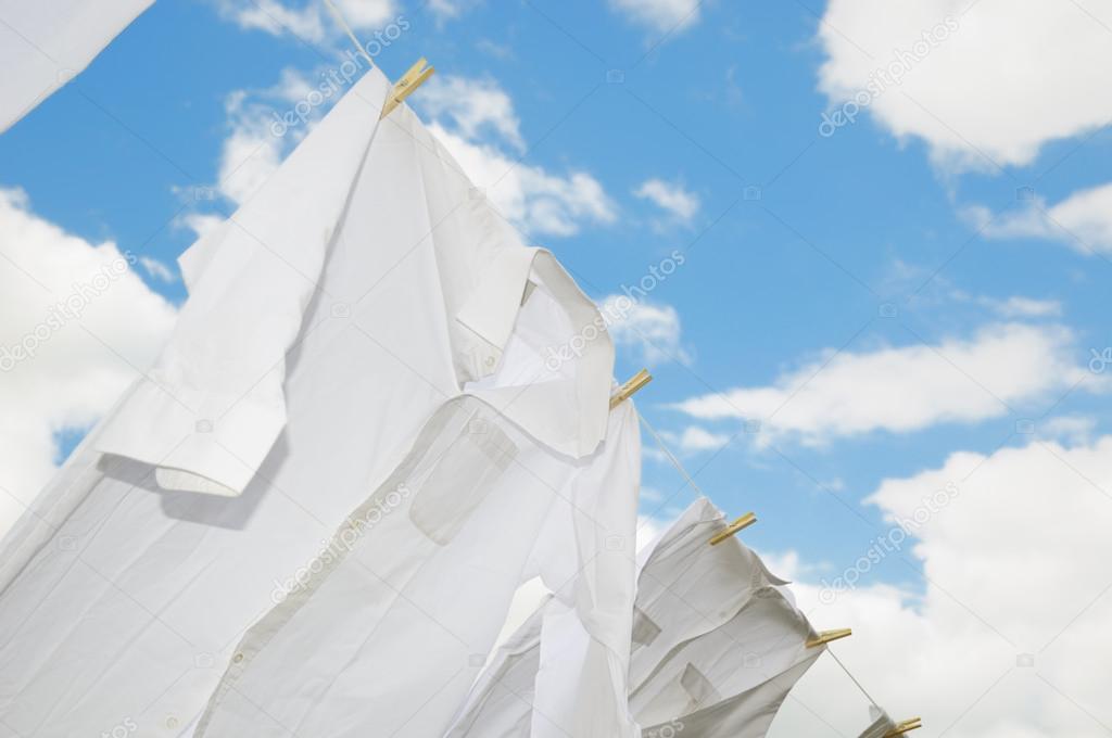 Fresh washed shirts drying on rope in bright day