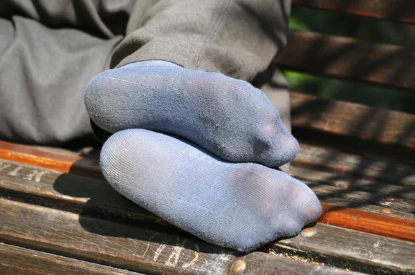 Legs of homeless person sleeping on the bench