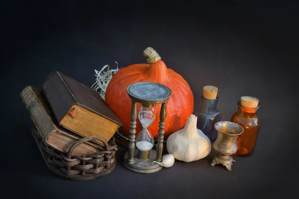 Libros de magia en cesta de la vendimia, reloj de arena, halloween pumpki — Foto de Stock