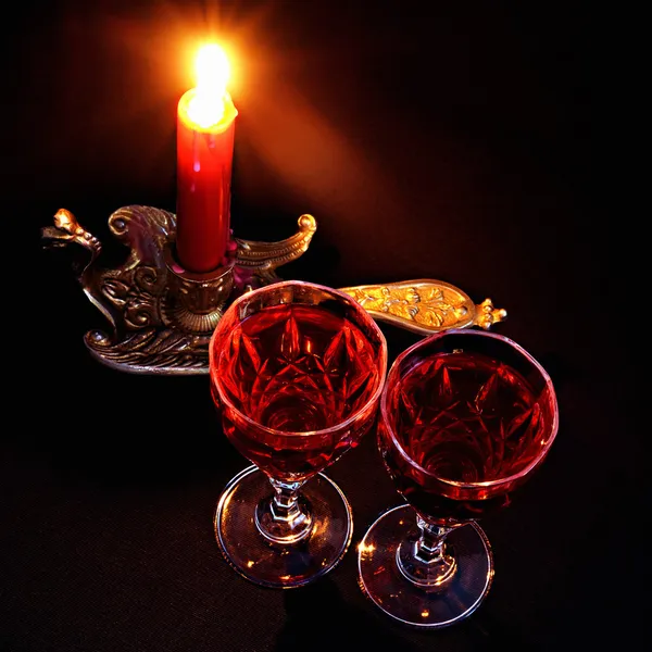 Красная свеча в винтажном подсвечнике и два бокала красного вина — стоковое фото