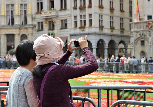 Turistas extranjeros toman fotos de la alfombra de flores —  Fotos de Stock