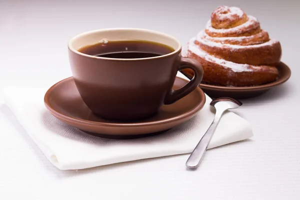 Tazza di tè nero su tovagliolo bianco con dolce panino — Foto Stock
