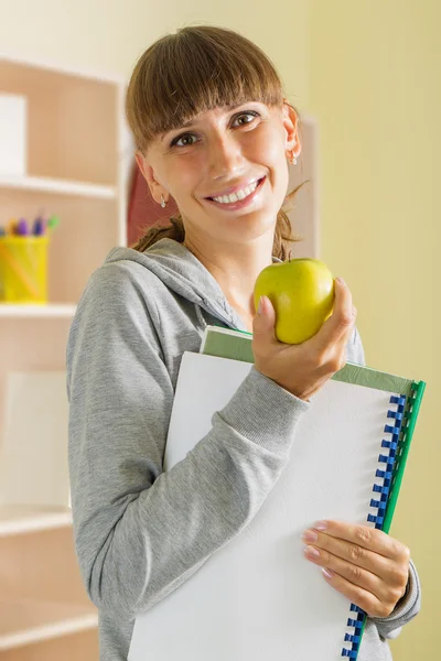 Giovane ragazza sorridente con mela e quaderni scolastici — Foto Stock