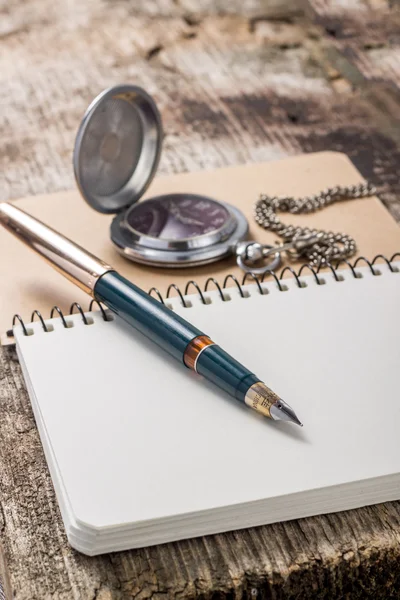 Oro en pluma con reloj de bolsillo en cuaderno blanco — Foto de Stock