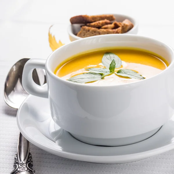 Pumpkin cream-soup in white bowl with silver spoon — Stock Photo, Image