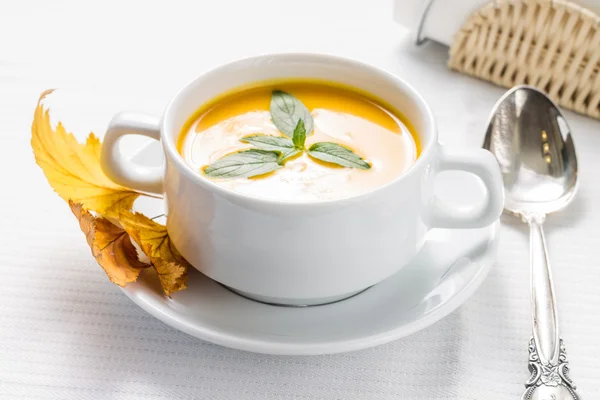 Pumpkin soup with basil on served table — Stock Photo, Image
